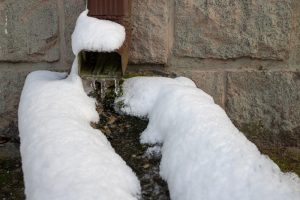 downspout with ice inside but clear of the snow around it