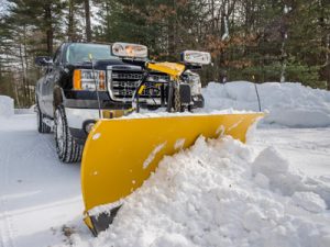truck with yellow straight plow on front pushing snow